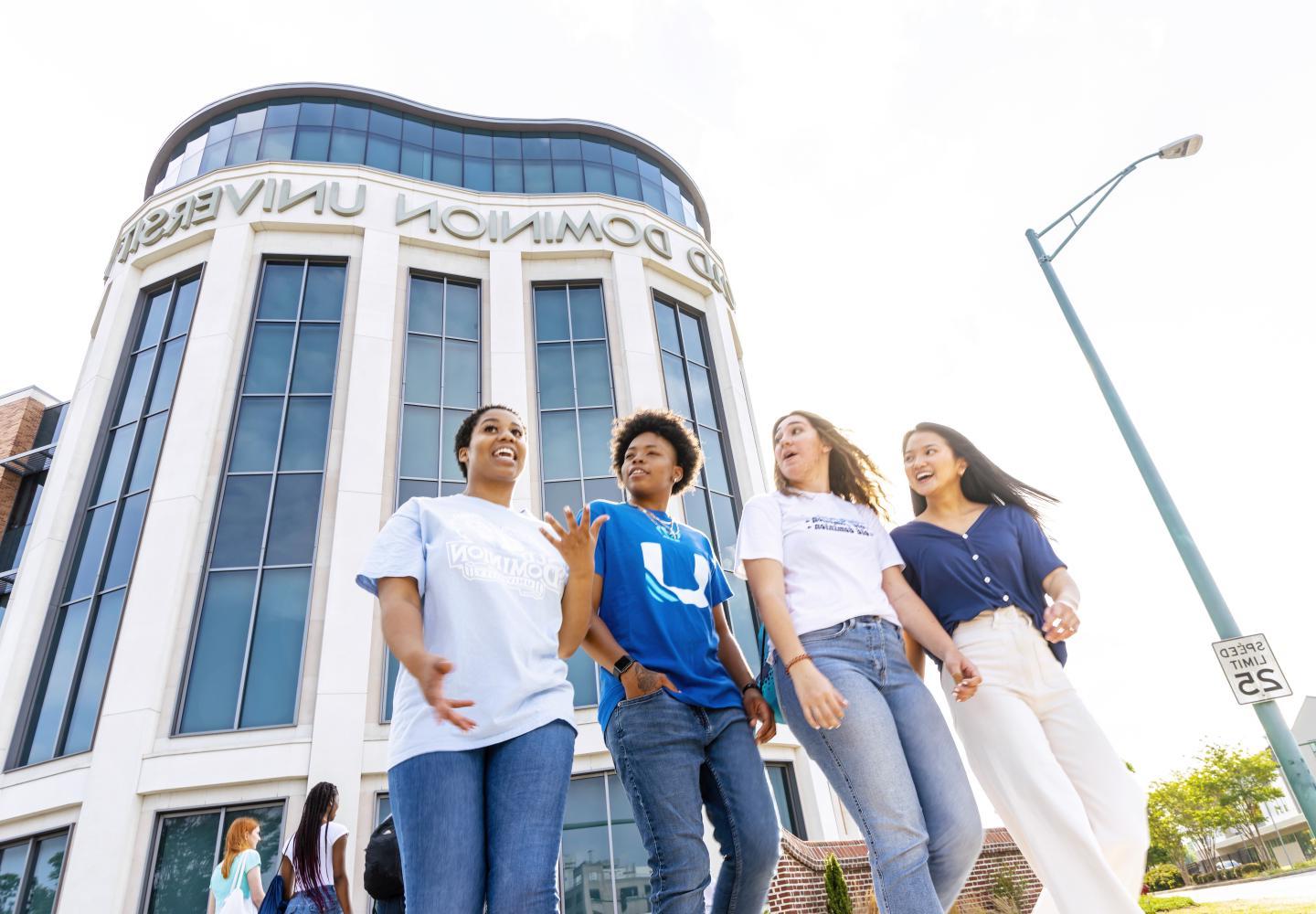 Four female students walking in front of the Education building while having a conversation